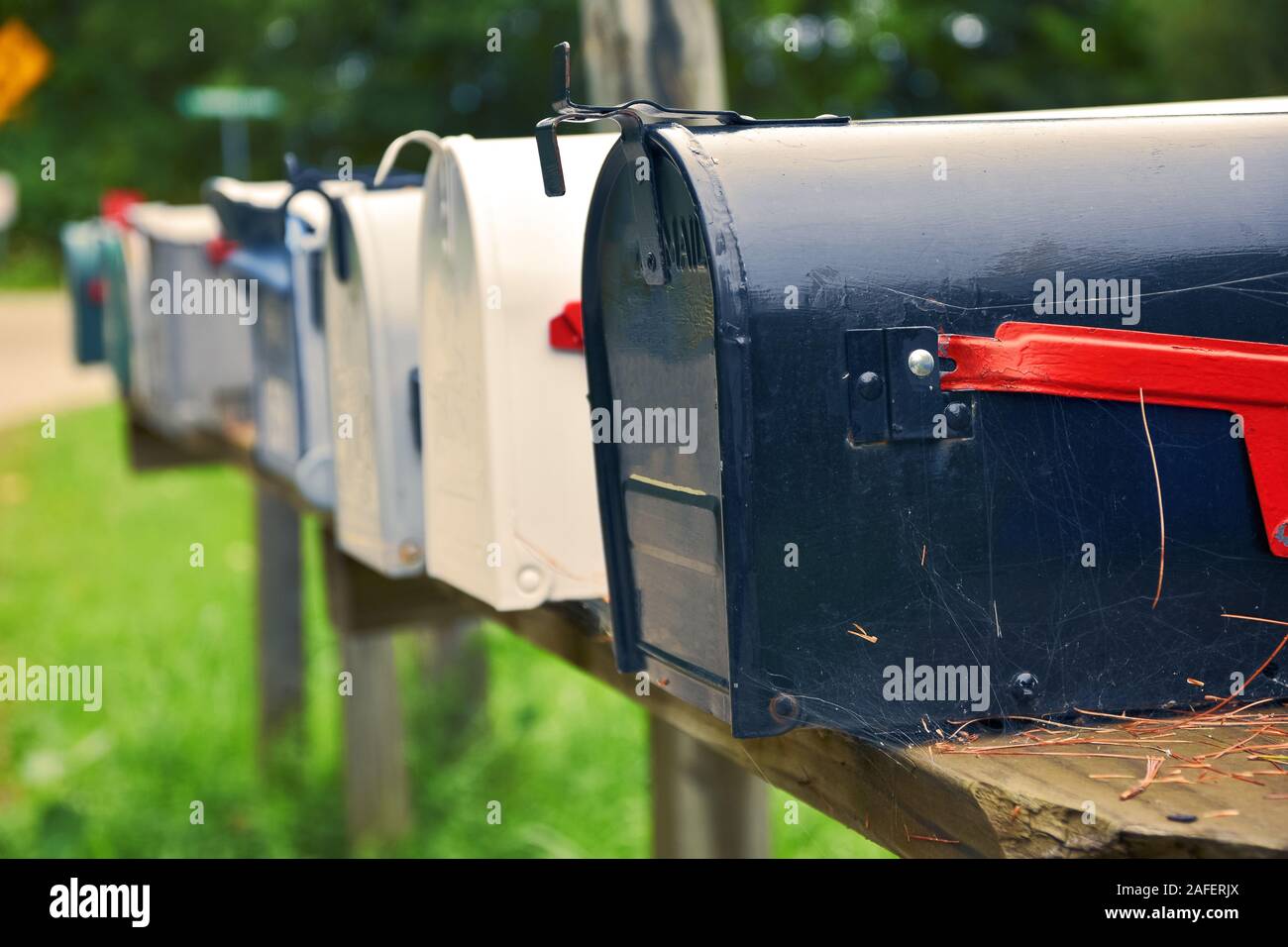 An isolated row of metal US mail boxes on wooden post in the countryside. Spider webs in one of them. Mail concept. New York City. United States. Stock Photo