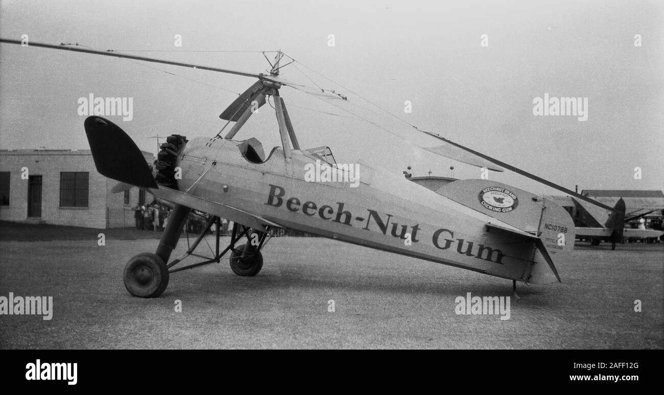 1931, historical, early hybrid helicopter-aircraft, the Pitcairn Auto Gyro  stationed outside a small airport building, USA. A mix of airplane and helicopter, the 'autogyro' had a rotor to lift it and engine-powered propeller for thrust, meaning it flew slowly, but could land in small places. Aviatrix Amelia Earhart undertook test flights in the unusual aircraft, branded with Beech-Nut chewing gum, across America 1931 as part of a publicity tour for her sponsor, the Beech Nut Packing Company. Spanish engineer Juan de le Cierva flew the first autogiro in 1923 in Madrid. Stock Photo