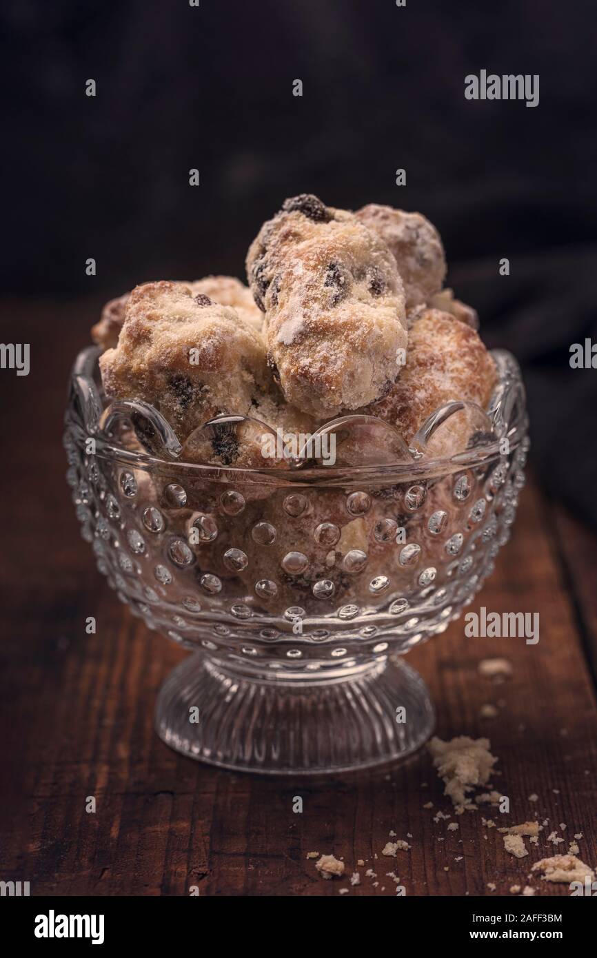Traditional German mini stollen cakes in a glass bowl on a rustic old table. With a dark background. Stock Photo