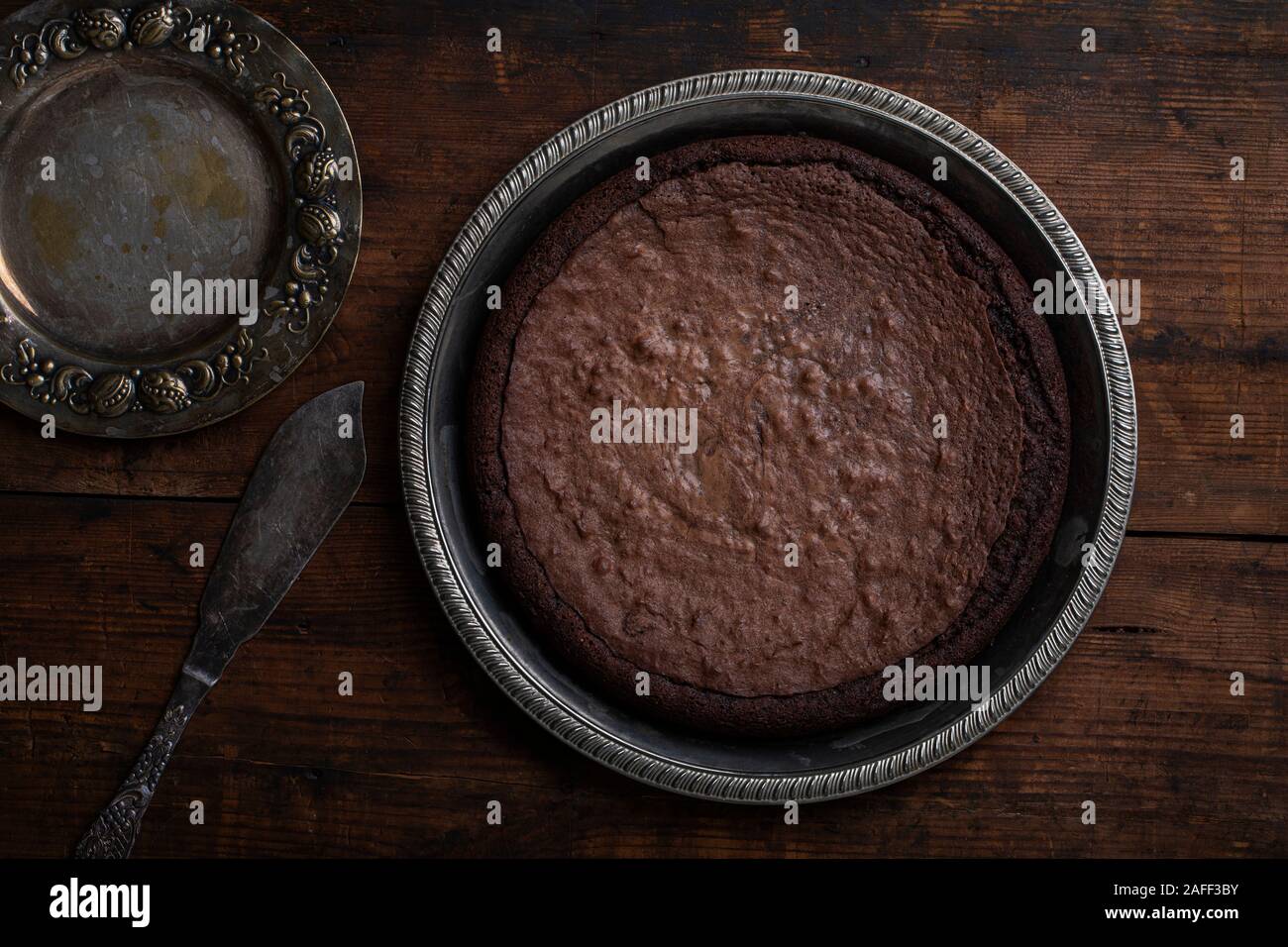 Chocolate mud cake swedish kladdkaka or sticky chocolate cake, seen from above.The cake is on a rustic vintage wooden table. Stock Photo
