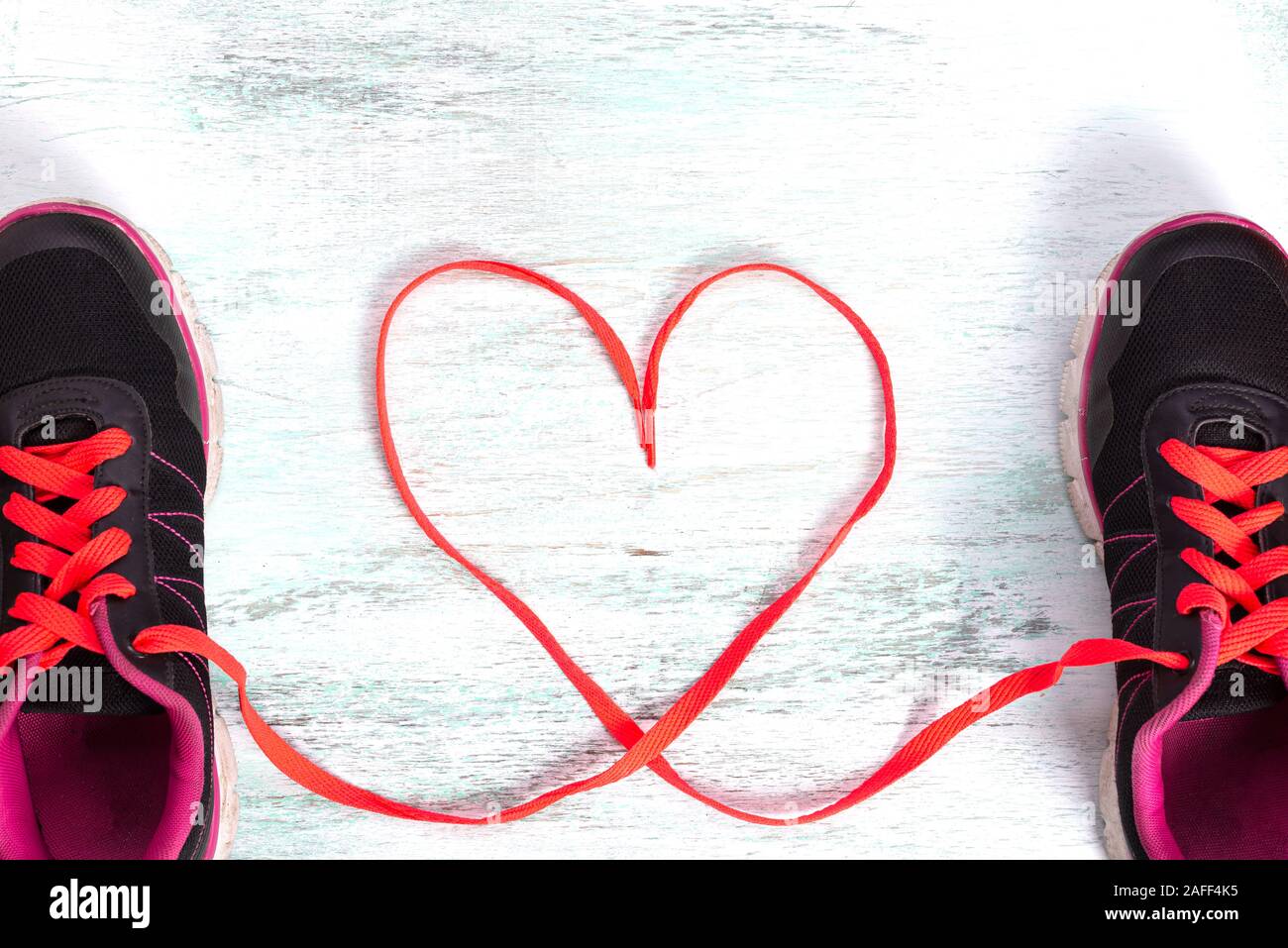 Top view of a pair of shoes with laces making heart shape on wooden