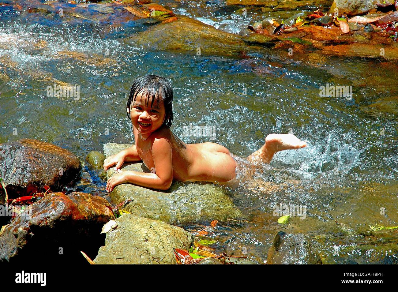 Kleines Maedchen schwimmt nackt im Bach Stock Photo