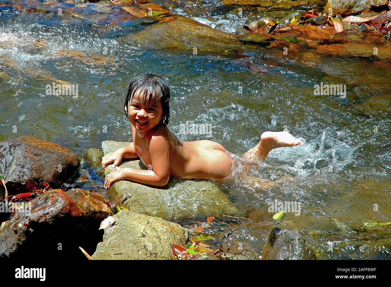Kleines Maedchen schwimmt nackt im Bach Stock Photo