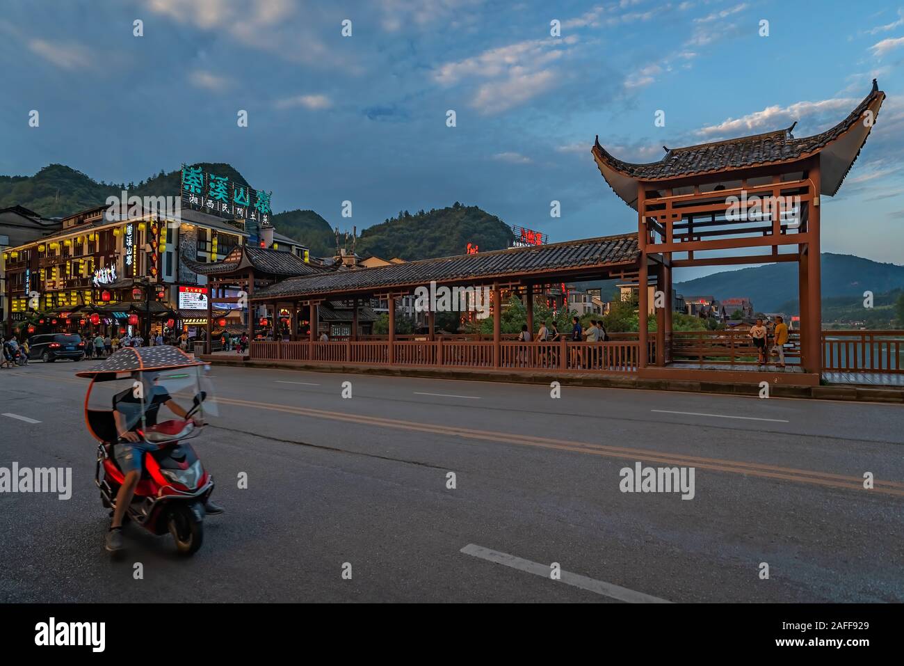 Wulingyuan, China -  August 2019 : Chinese man riding on a motorbike on a street in the ancient part of Wullingyuan town Stock Photo