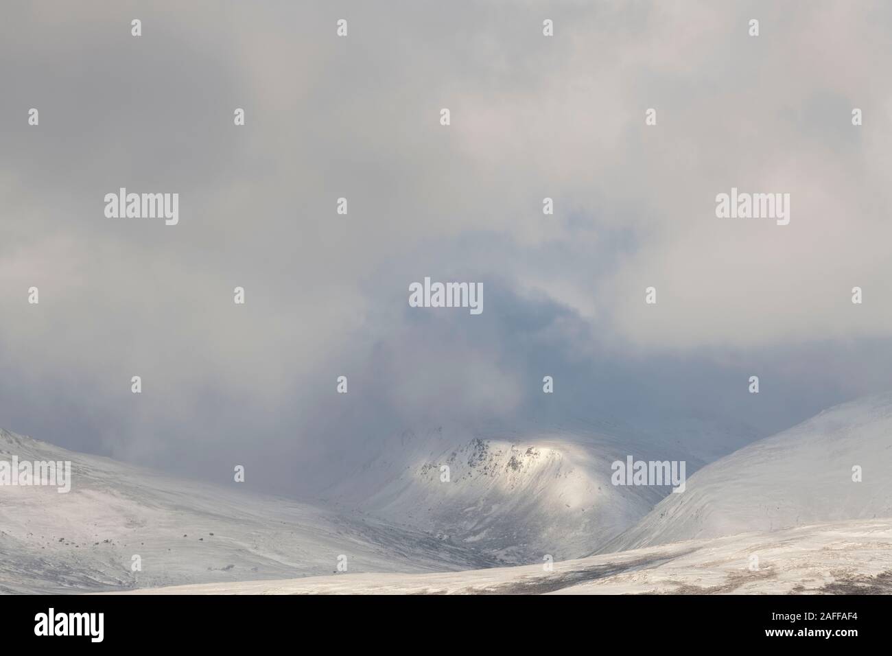 The Scottish Highlands in Winter, Where a Patch of Sunshine Lights Up a Rocky Ridge on Meall an t-Slugain, the Summit of Which is Hidden in Cloud Stock Photo