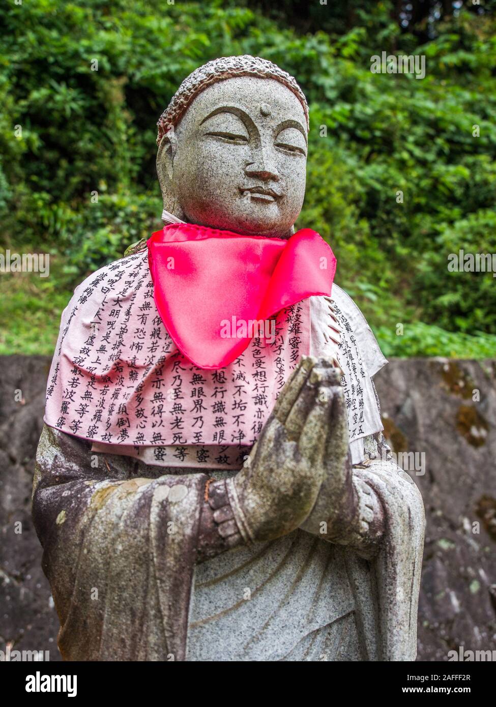 Buddhist statue, praying mudra, with red bib and kanji sutra shawl