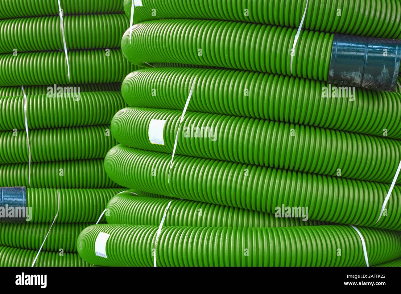 Coils of new red plastic pipe with rain drops. Red plastic tubing for underground cable