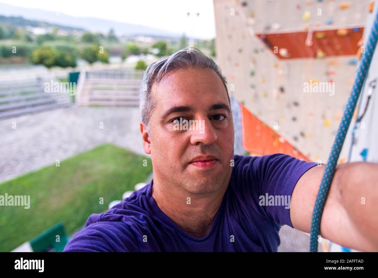 Man wearing belaying rope, climbing on a very high rock climbing wall ...