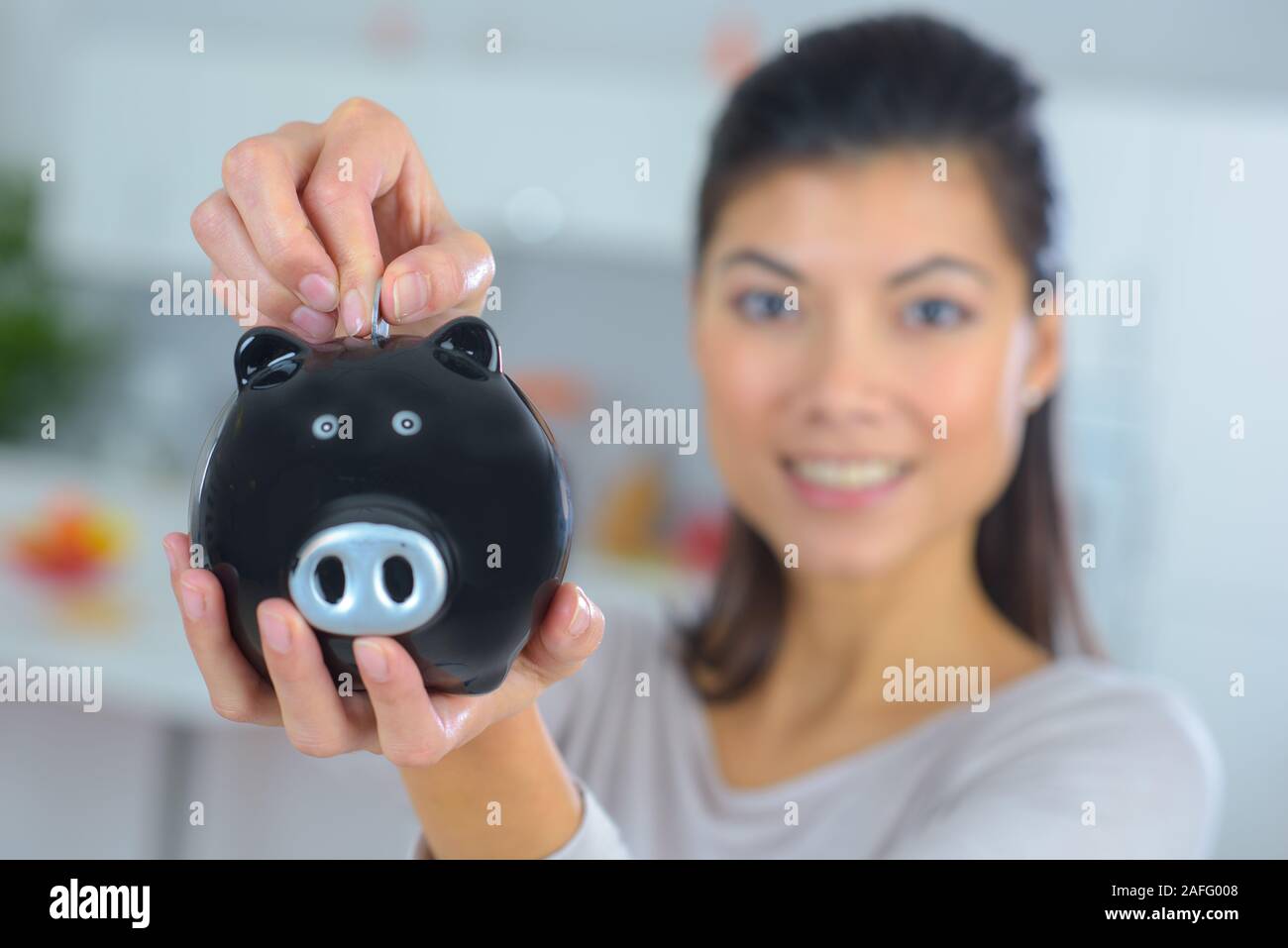 woman putting money into piggy bank at home Stock Photo - Alamy