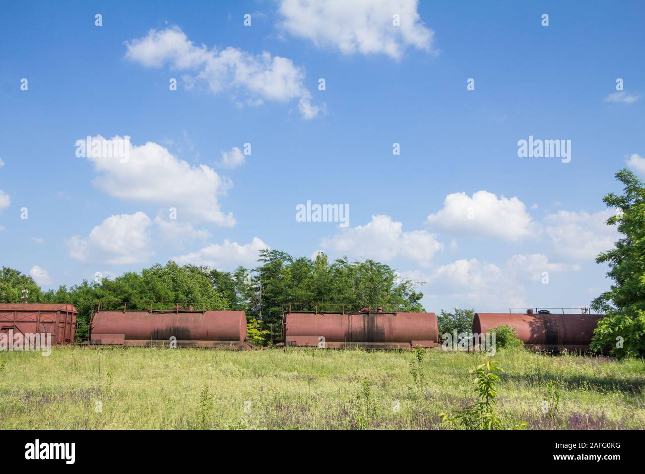 Abandoned wagons, old and rusty tank cars that used to carry oil, on display on a decommissioned railway train track that was left unused since the ec Stock Photo