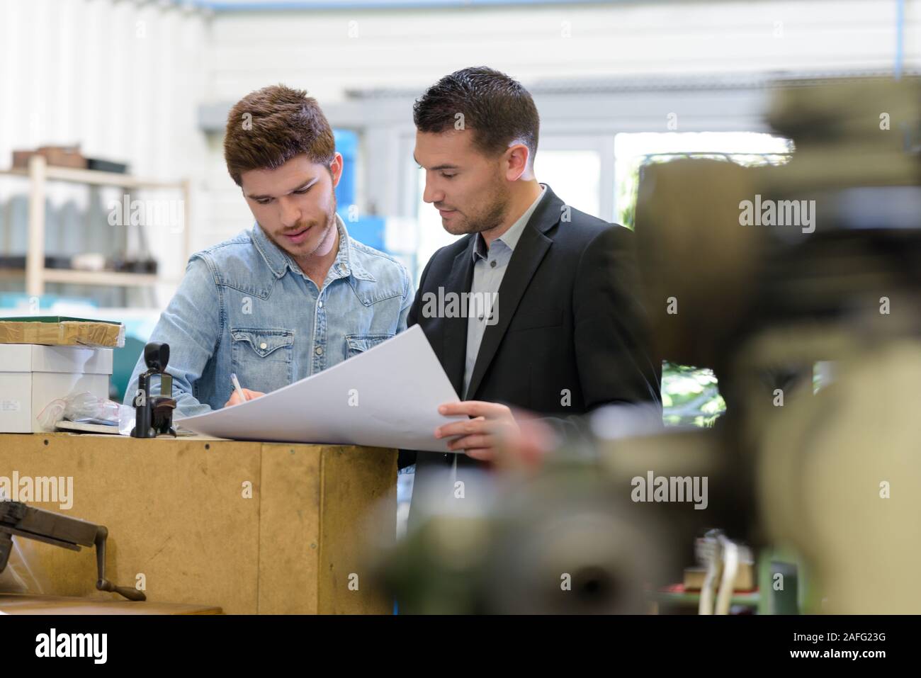 man working with apprentice in printing house Stock Photo