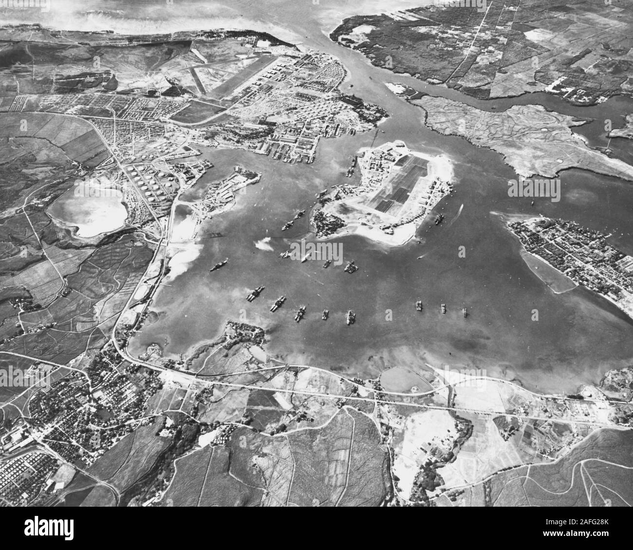 Aerial view of the Naval Operating Base, Pearl Harbor, looking southwest on 30 October 1941. Ford Island Naval Air Station is in the center, with the Pearl Harbor Navy Yard just beyond it, across the channel. The airfield in the upper left-center is the Army's Hickam Field. Stock Photo