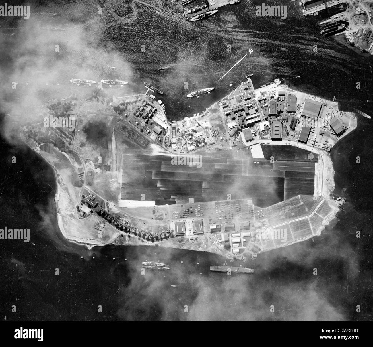 Pearl Harbor, Oahu, Hawaii - Aerial photograph of Ford Island, taken 22 October 1941. USS Saratoga (CV-3) is moored in the lower right center, on Ford Island's northwestern side. Three battleships and an oiler are moored along Battleship Row, on the island's southeastern side. Another battleship is alongside 1010 dock, in the top center. In the extreme top right corner is the Navy Yard's Drydock Number Two, under construction, and floating drydock YFD-2. Approximately 22 PBY patrol planes parked at the Naval Air Station's seaplane base, on the upper right point of Ford Island. Before WWII Stock Photo