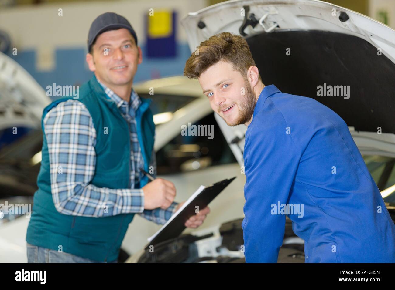 portrait of a mechanics taking notes and smiling Stock Photo - Alamy