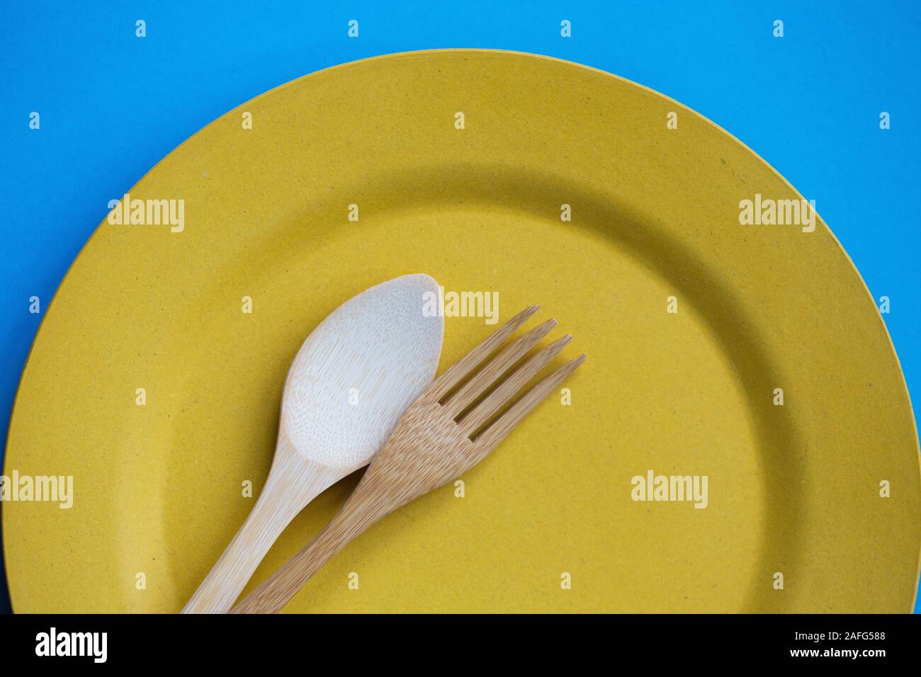 Bamboo cutlery on a yellow plate. Stock Photo