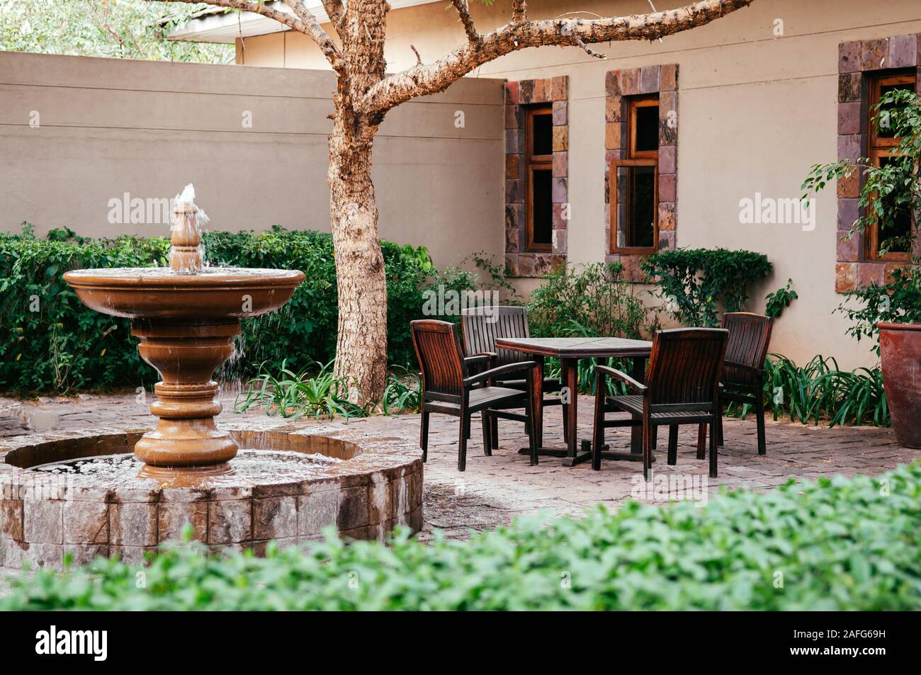 Jun 19 2011 Serengeti Tanzania Fountain And Old Wooden Chairs And Table Set In Tropical Backyard Garden Under Tree With Green Shrubs Under Natu Stock Photo Alamy