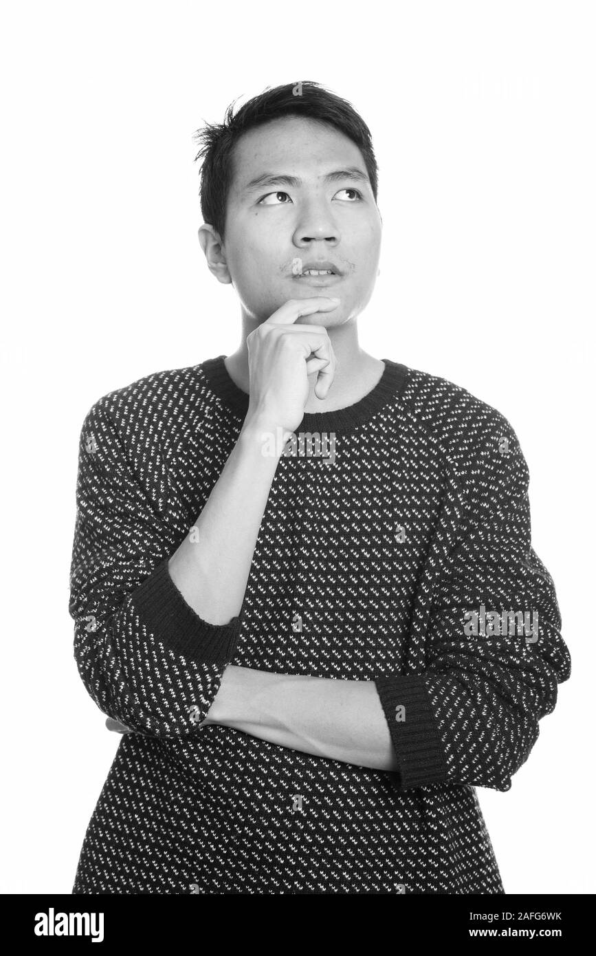 Studio shot of young Asian man thinking Stock Photo