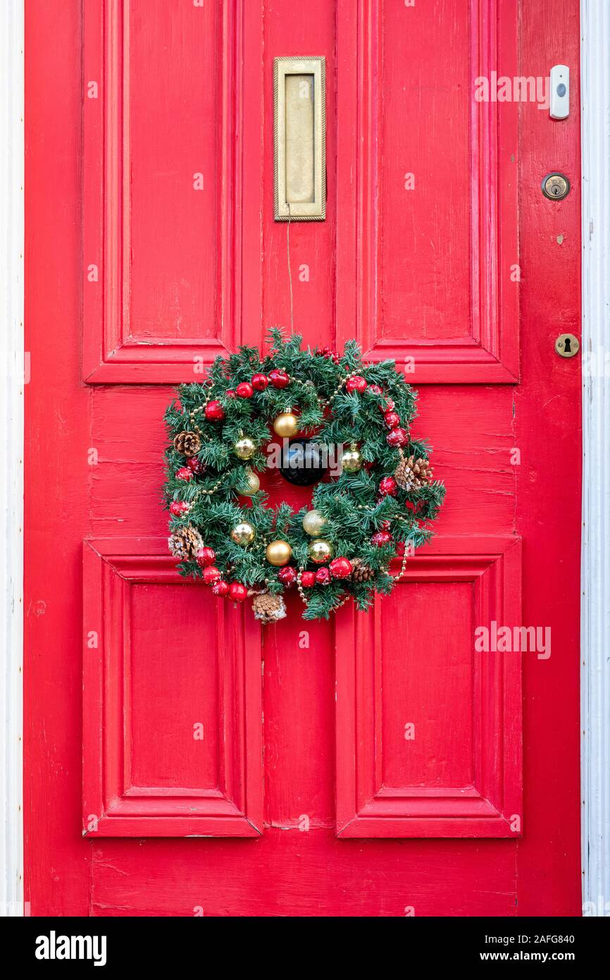 Christmas wreath on a red house door in Moreton in Marsh. Cotswolds, Gloucestershire, England Stock Photo