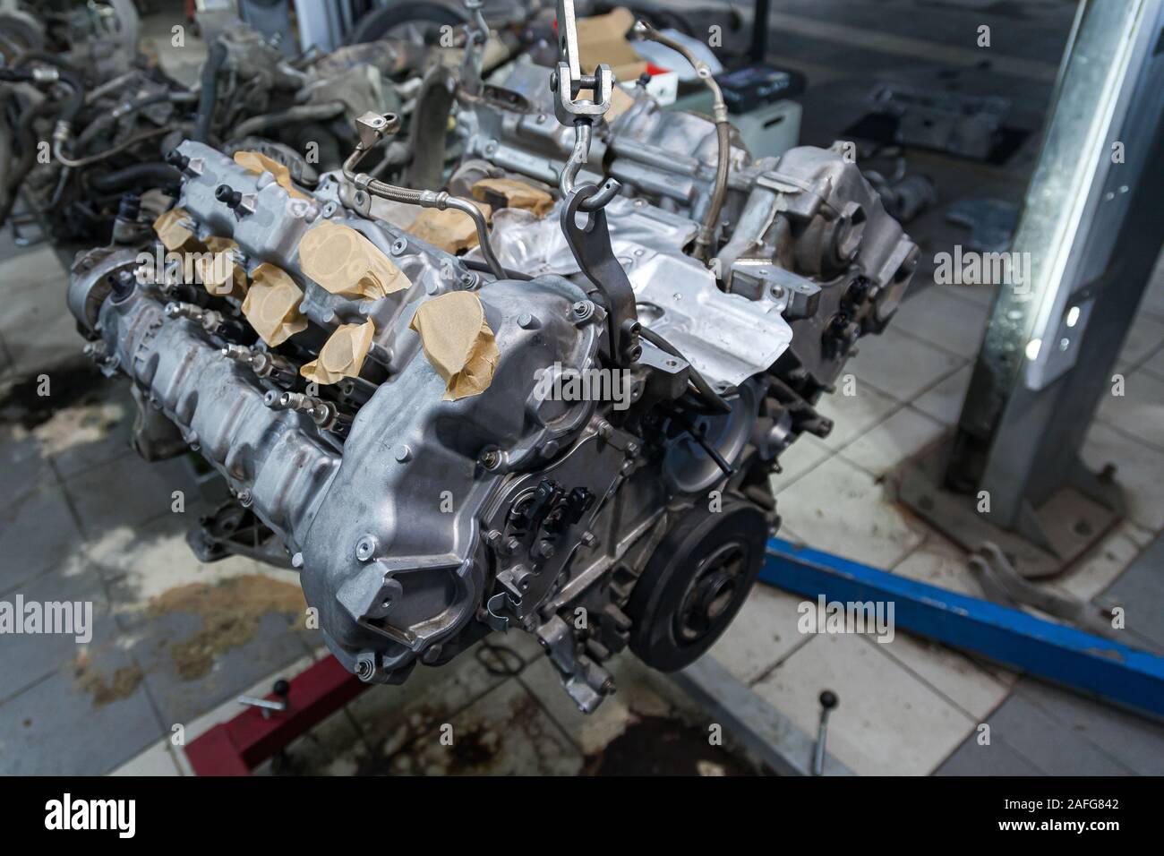 Used v8 engine with eight cylinders suspended mounted on a crane for