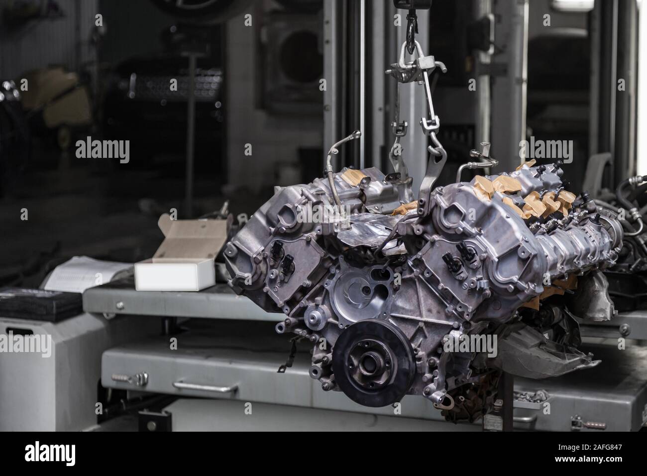 Used v8 engine with eight cylinders suspended mounted on a crane for