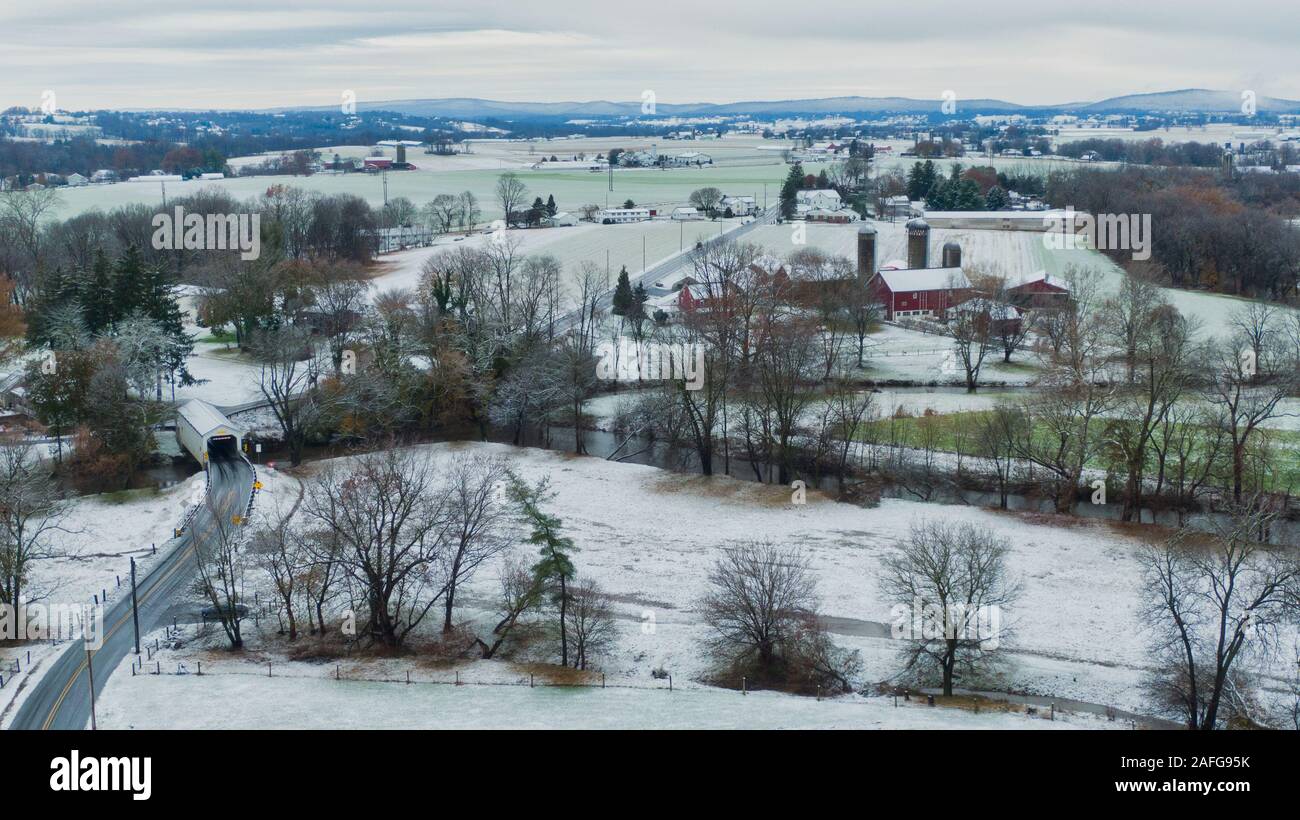 Pennsylvania aerial landscape in first snow, traditional farm and covered bridge, Keller's Mill in Lancaster County, PA Stock Photo