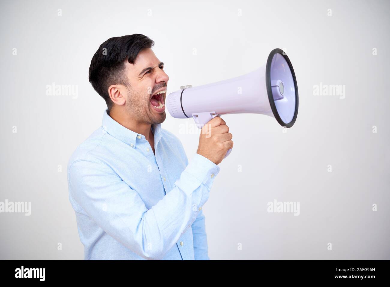 Studio shoot of young entrepreneur making announcement and shouting in megaphone Stock Photo