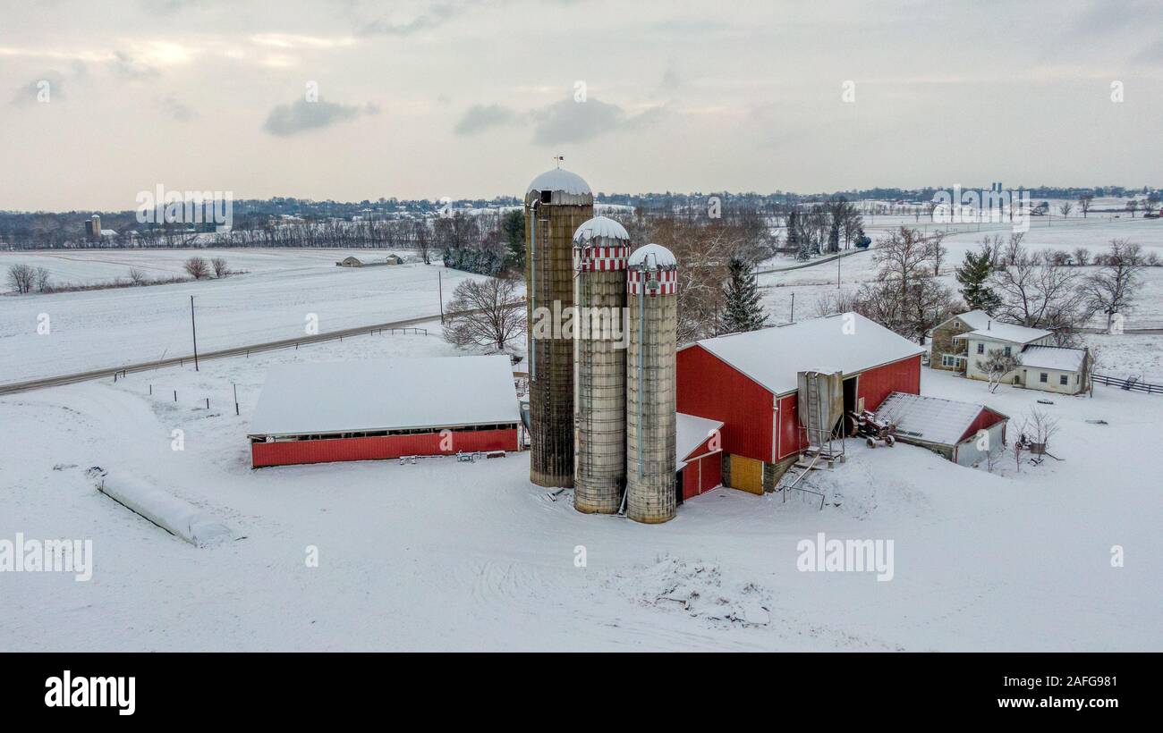 Farm in winter, red house and barn in white snow landscape, aerial view of rural countryside in Pennsylania, America Stock Photo