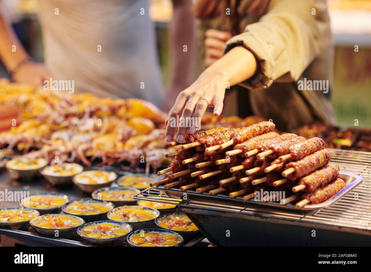 Female customer taking skewer with fried meet from stall with Asian street  food Stock Photo - Alamy