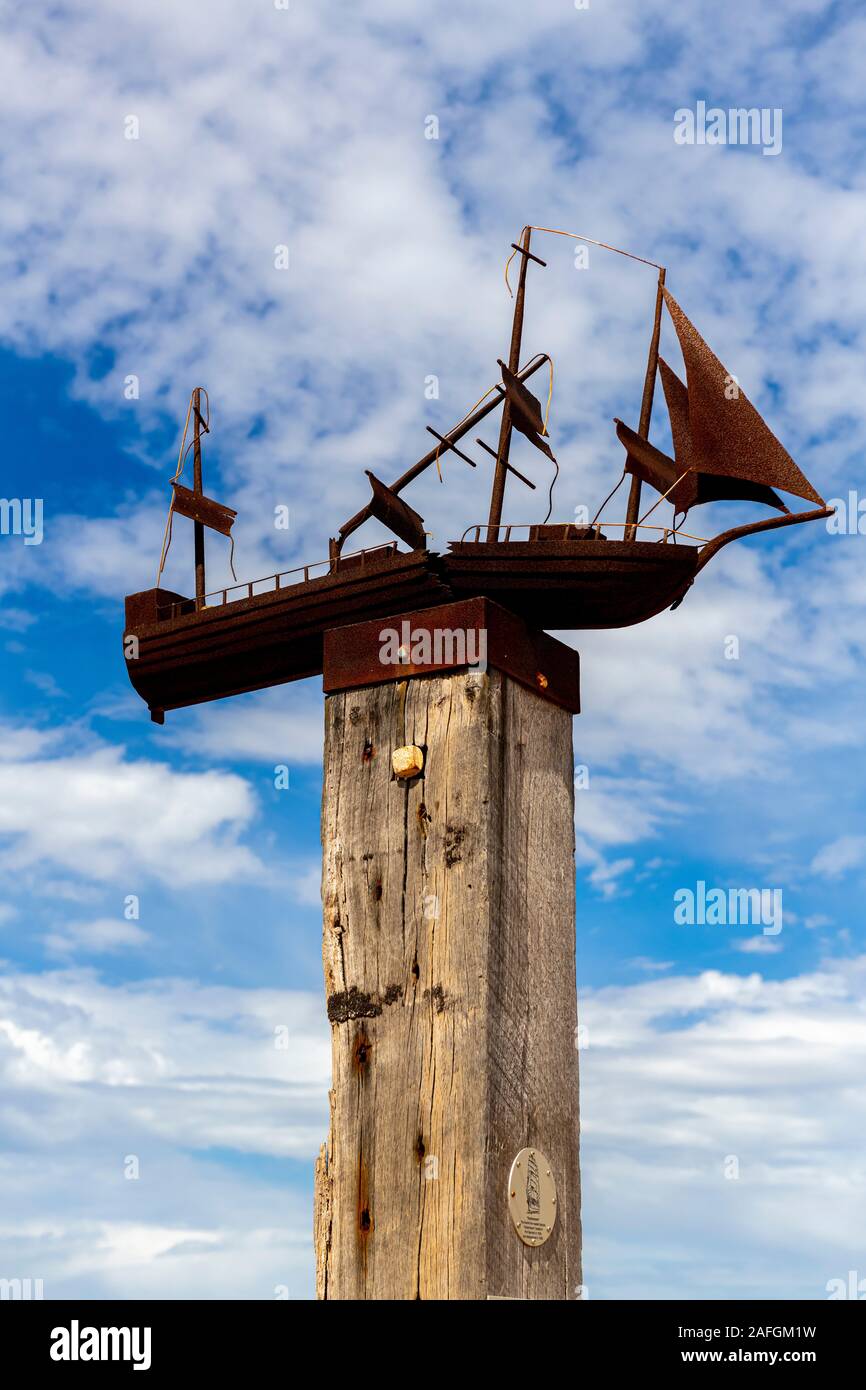 An outdoor sculpture of a rusted wooden sailing boat sits on top of a wooden pole at Port Germein jetty in South Australia Stock Photo