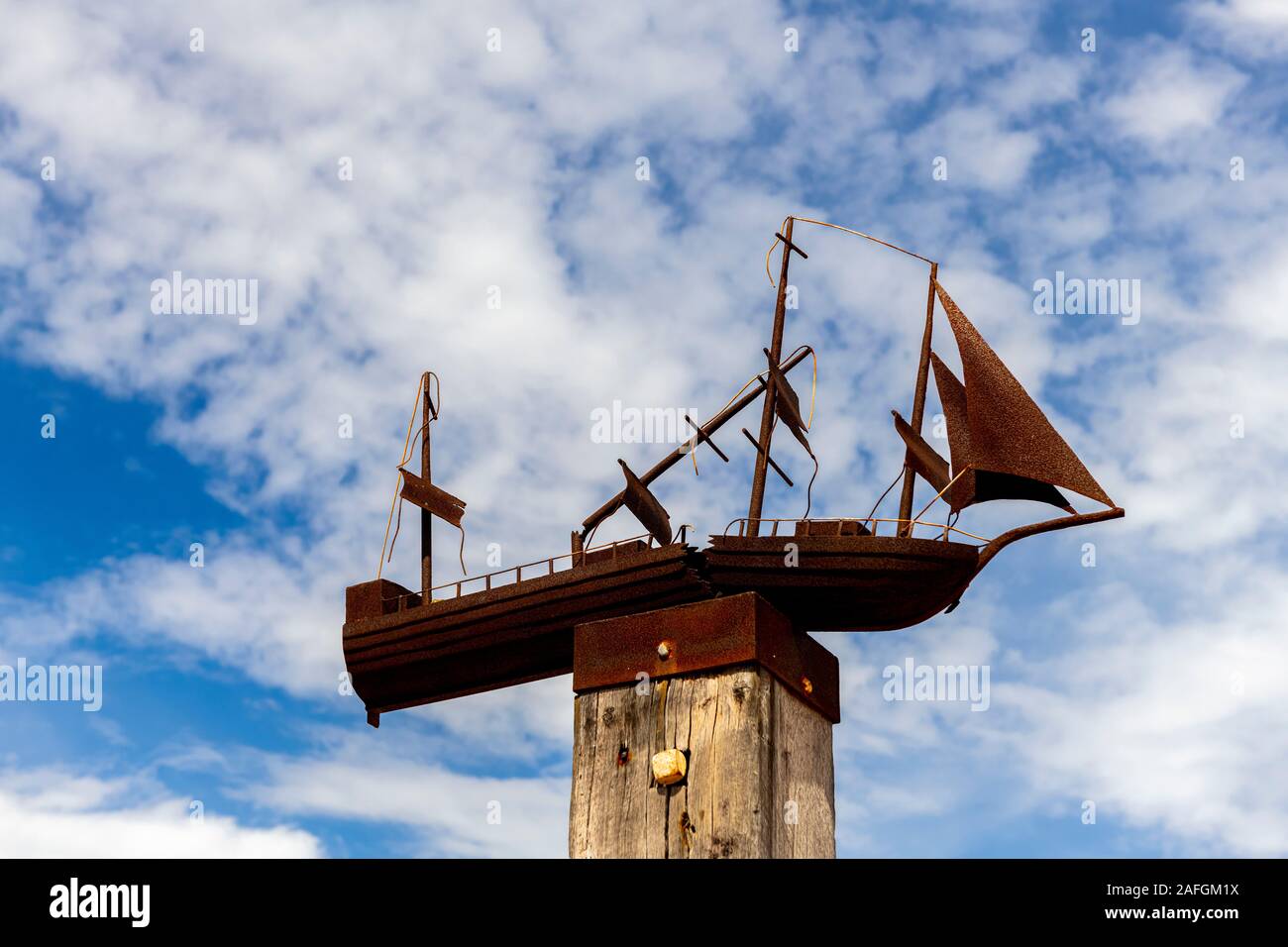An outdoor sculpture of a rusted wooden sailing boat sits on top of a wooden pole at Port Germein jetty in South Australia Stock Photo