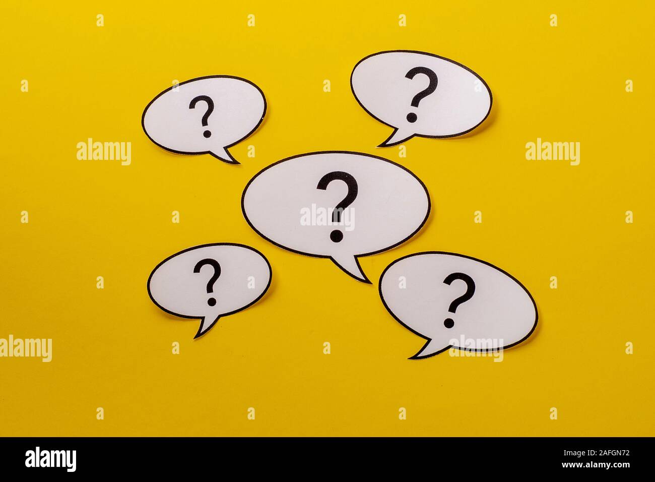 Five speech bubbles with question marks over a bright yellow background Stock Photo