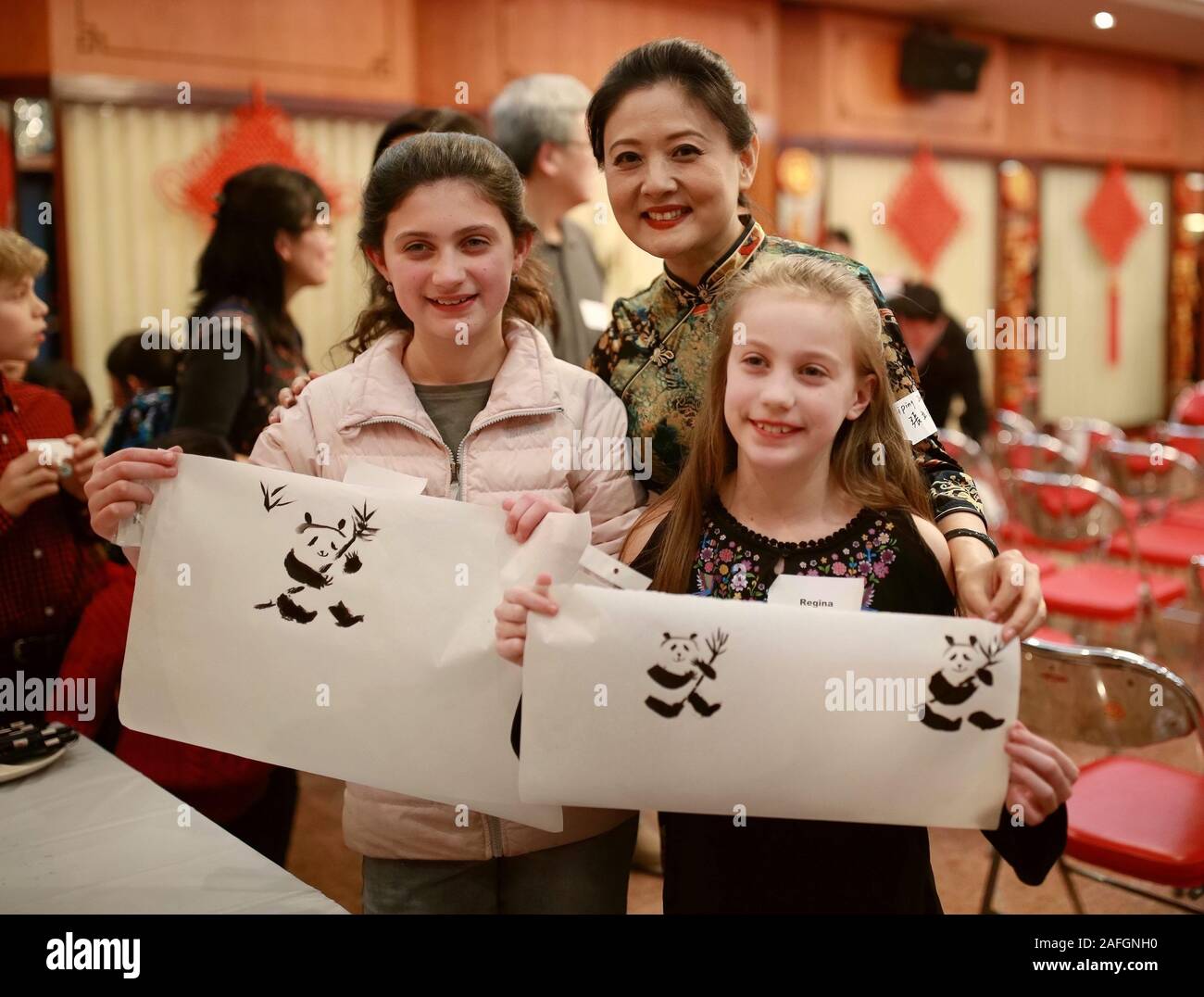 (191216) -- CHICAGO, Dec. 16, 2019 (Xinhua) -- Two girls show their paintings of panda with Chinese traditional painting artist Zhang Liping (C) during the event 'From China to Chicago: A Holiday Gathering & Celebration' in Chicago, the United States, on Dec.14, 2019. More than 15 children adopted from China and their American parents, siblings attended a cultural event organized by Chinese diplomats in Chicago on Saturday. The event, 'From China to Chicago: A Holiday Gathering & Celebration,' was held at the Chinese Consulate General in Chicago and involved several elaborate Chinese cultu Stock Photo