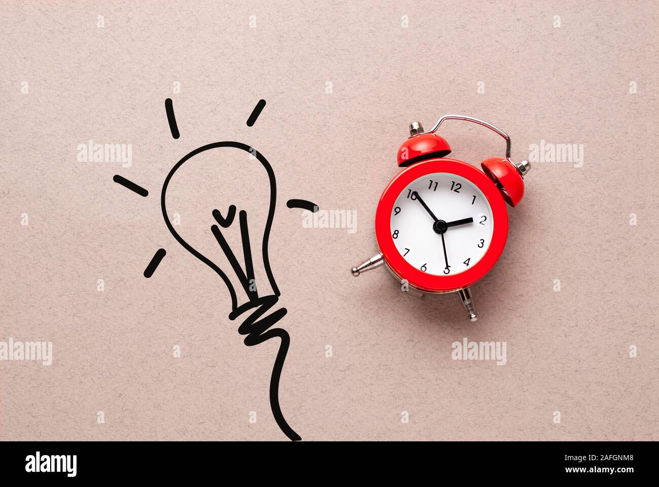 Red alarm clock alongside a sketch of a light bulb Stock Photo Alamy