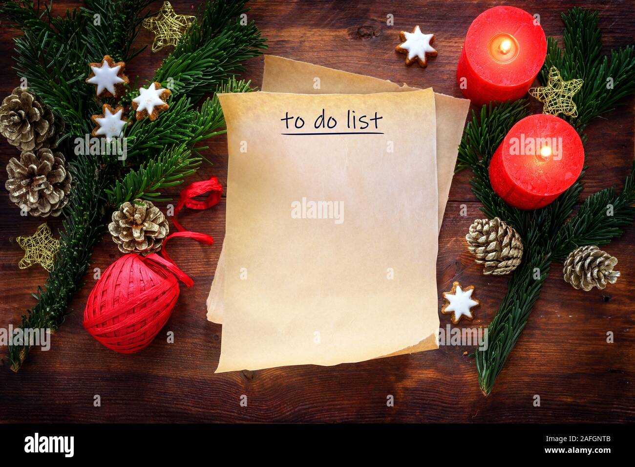 Paper sheet with text To Do List on rustic dark wood with burning red candles, fir branches, cinnamon stars and Christmas decoration, copy space, top Stock Photo