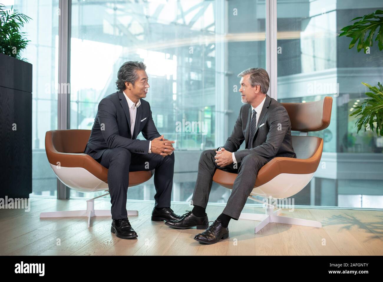 Two businessmen talking in office Stock Photo - Alamy