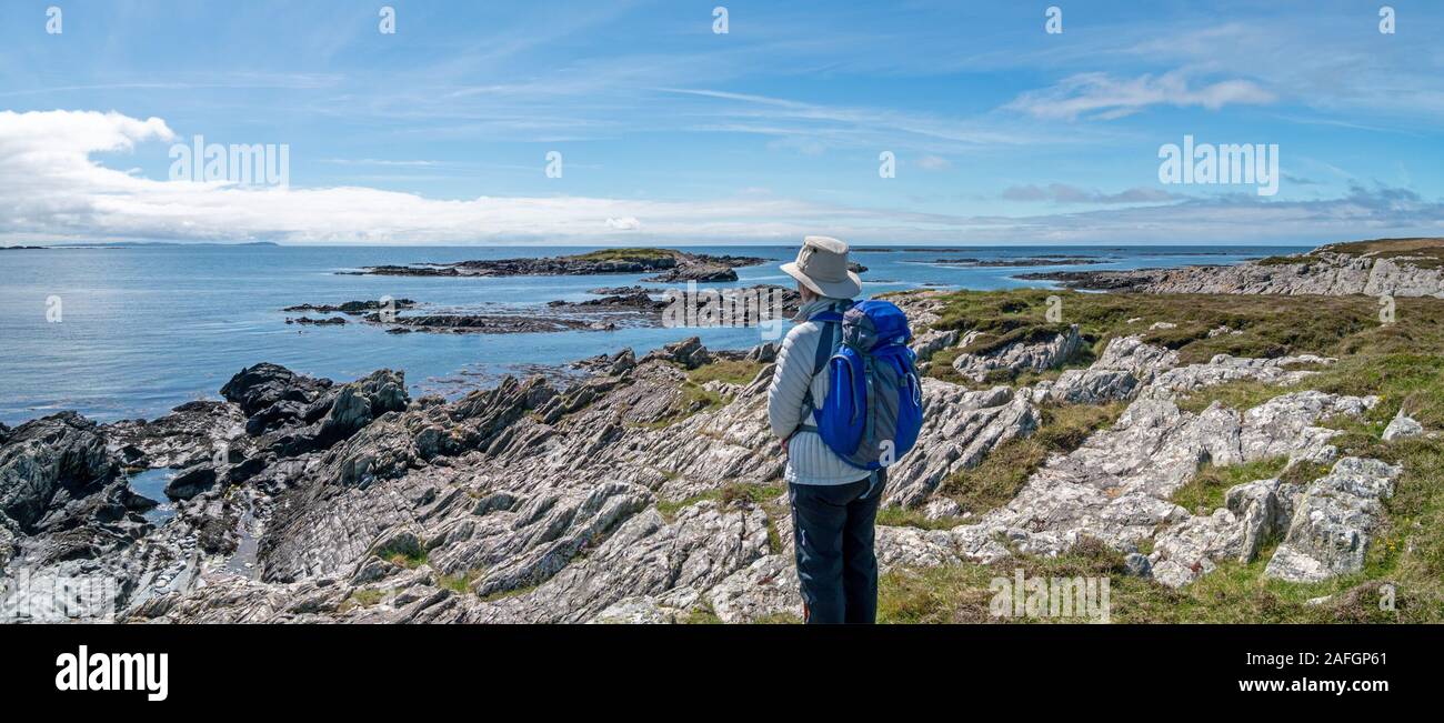 Holidaymaker admires panoramic view of Atlantic Ocean and coastline near Ardskenish, Island of Colonsay, Scotland, UK Stock Photo
