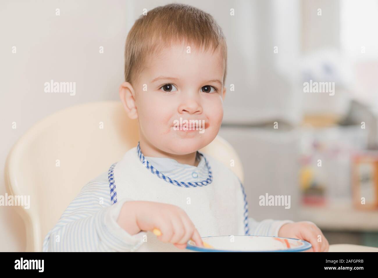 child in the kitchen eating fruit puree Stock Photo - Alamy
