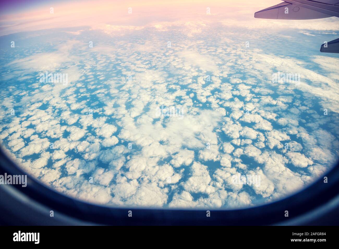 Airplane flying above clouds. The view through the porthole Stock Photo