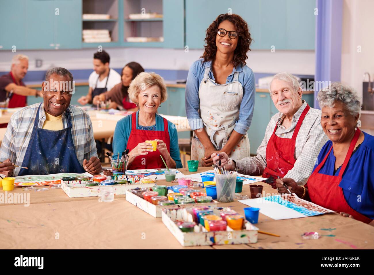 Portrait Of Retired Seniors Attending Art Class In Community Centre With Teacher Stock Photo