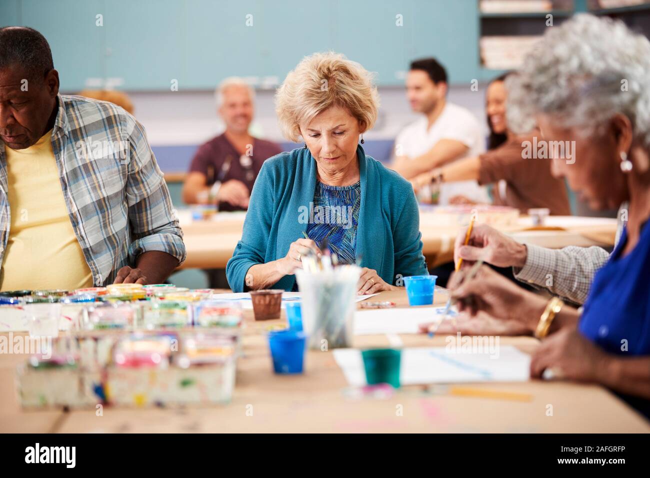 Group Of Retired Seniors Attending Art Class In Community Centre With