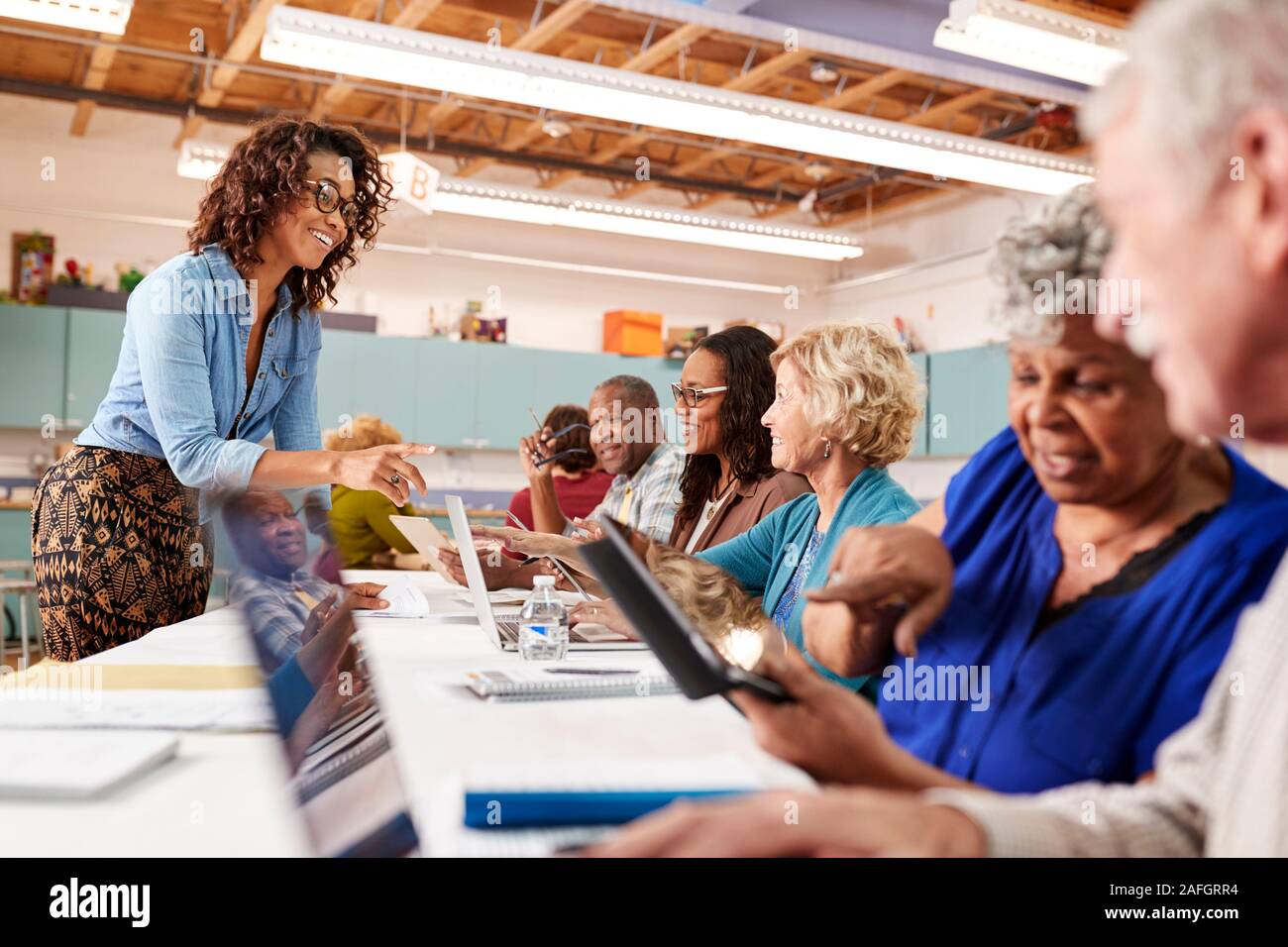 Group Of Retired Seniors Attending IT Class In Community Centre With Teacher Stock Photo