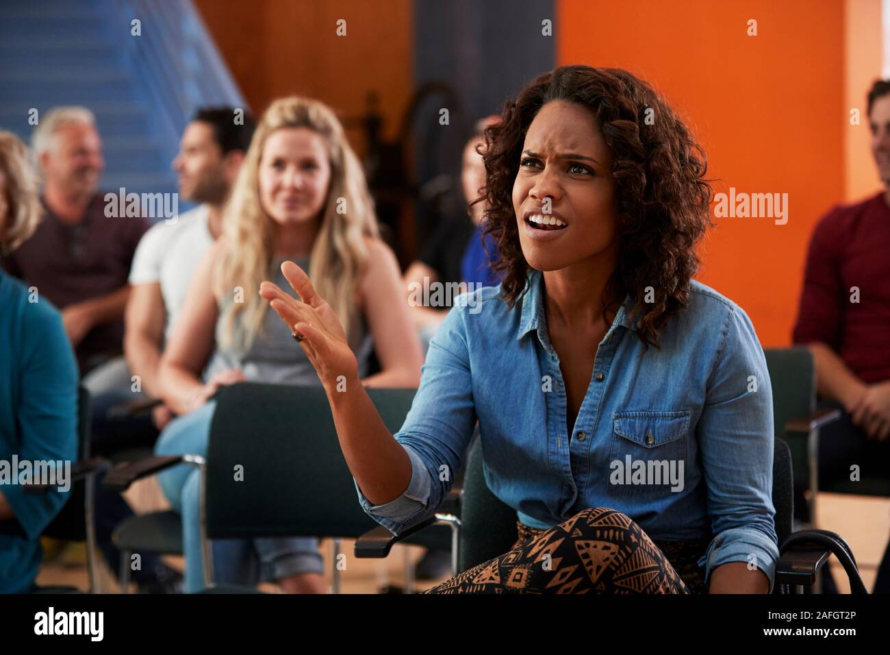 Frustrated Woman Asking Question At Group Neighborhood Meeting In Community Center Stock Photo