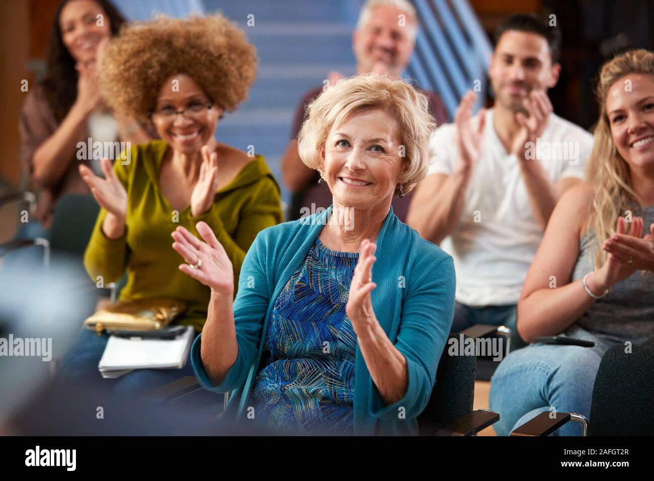 Group Attending Neighborhood Meeting Applauding Speaker In Community Center Stock Photo