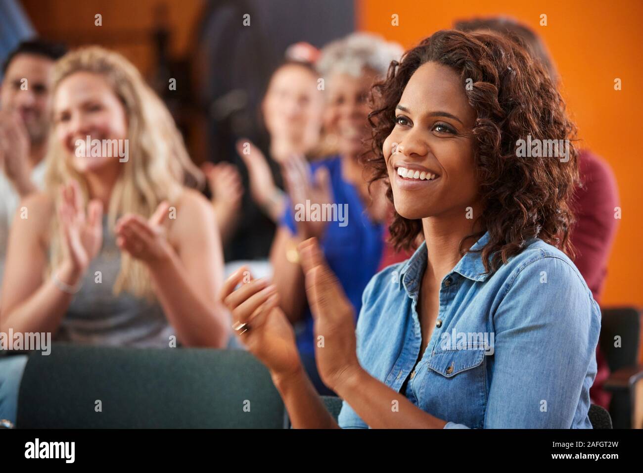 Group Attending Neighborhood Meeting Applauding Speaker In Community Center Stock Photo