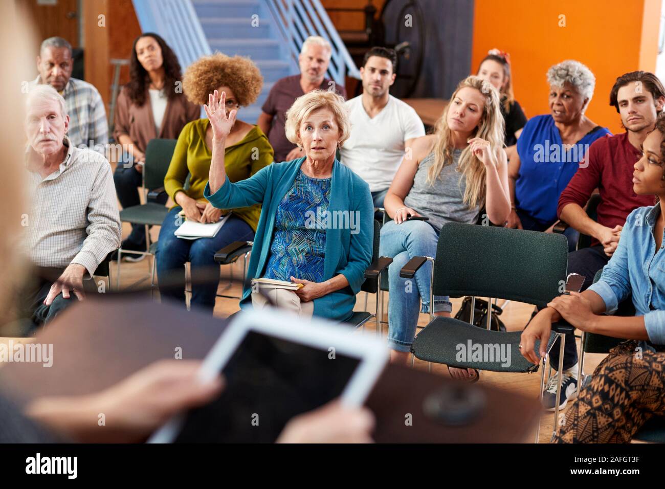 Woman Asking Question At Group Neighborhood Meeting In Community Center Stock Photo