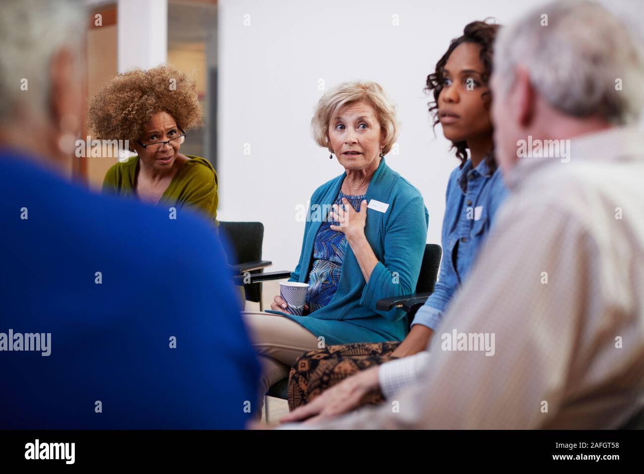 People Attending Self Help Therapy Group Meeting In Community Center Stock Photo