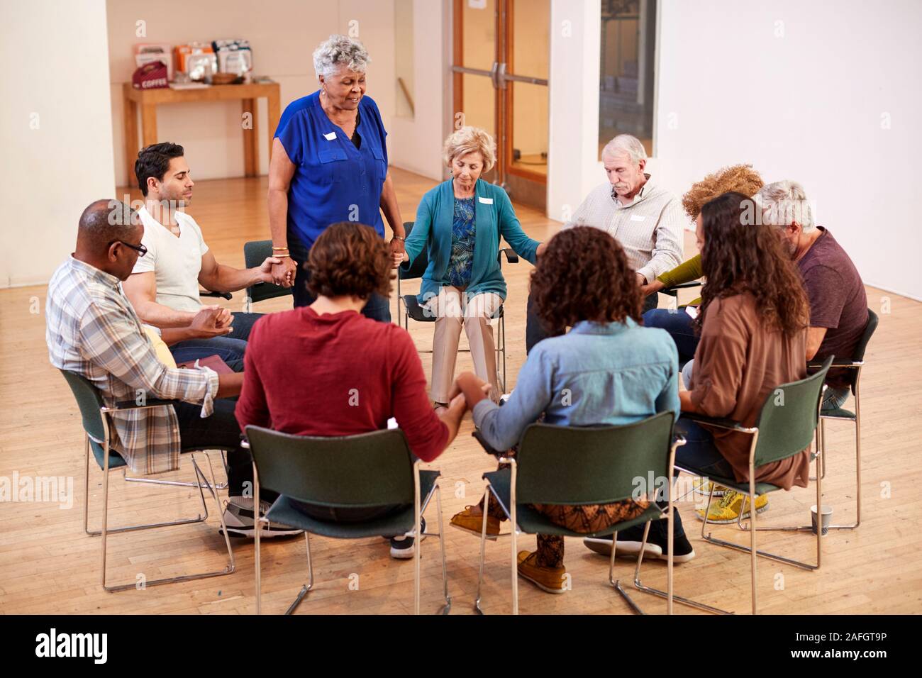 People Holding Hands And Praying At Bible Study Group Meeting In Community Center Stock Photo