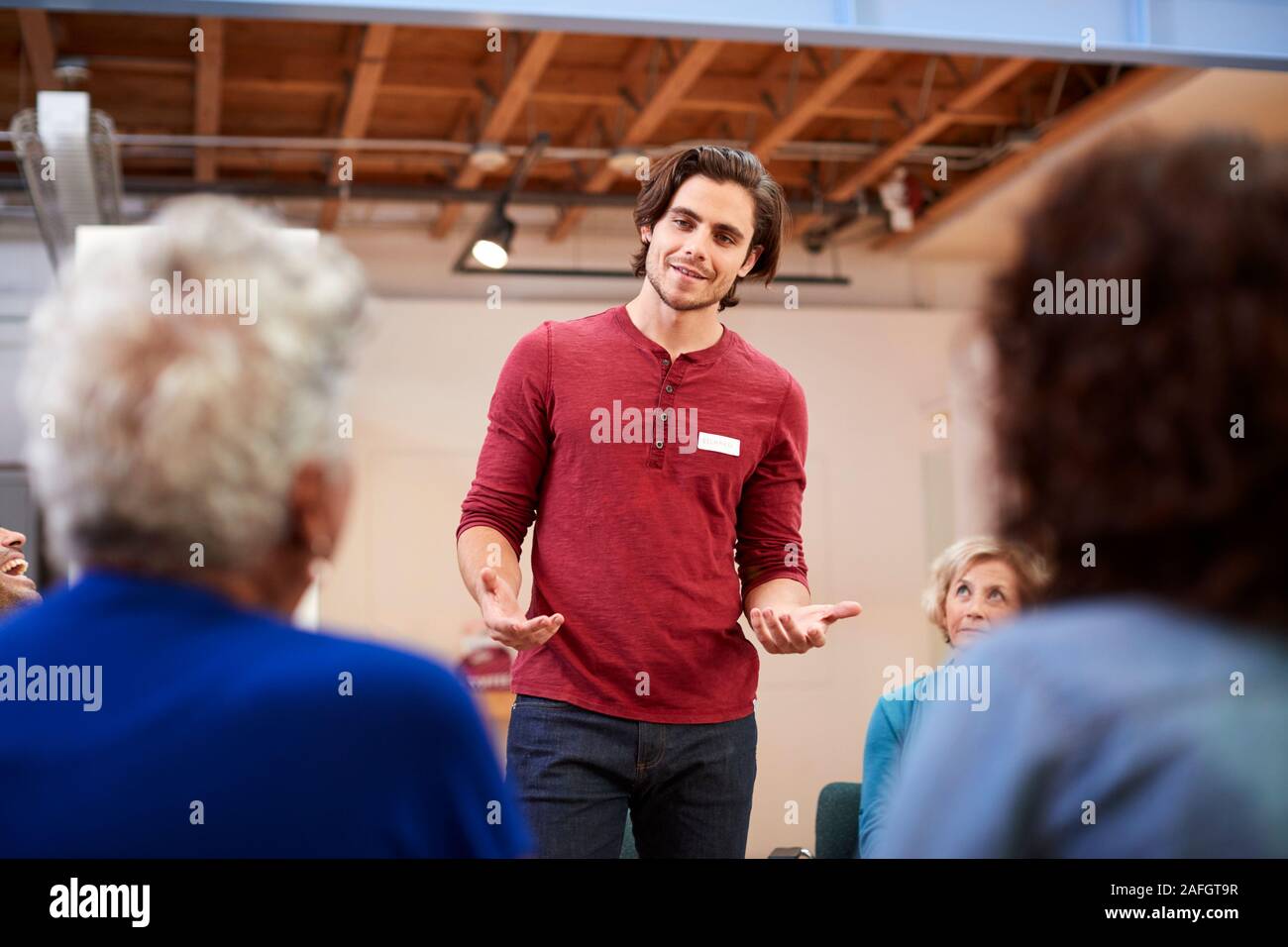 Man Standing To Address Self Help Therapy Group Meeting In Community Center Stock Photo