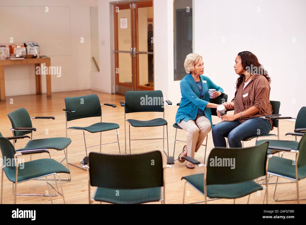 Two Women Talking After Meeting In Community Center Stock Photo