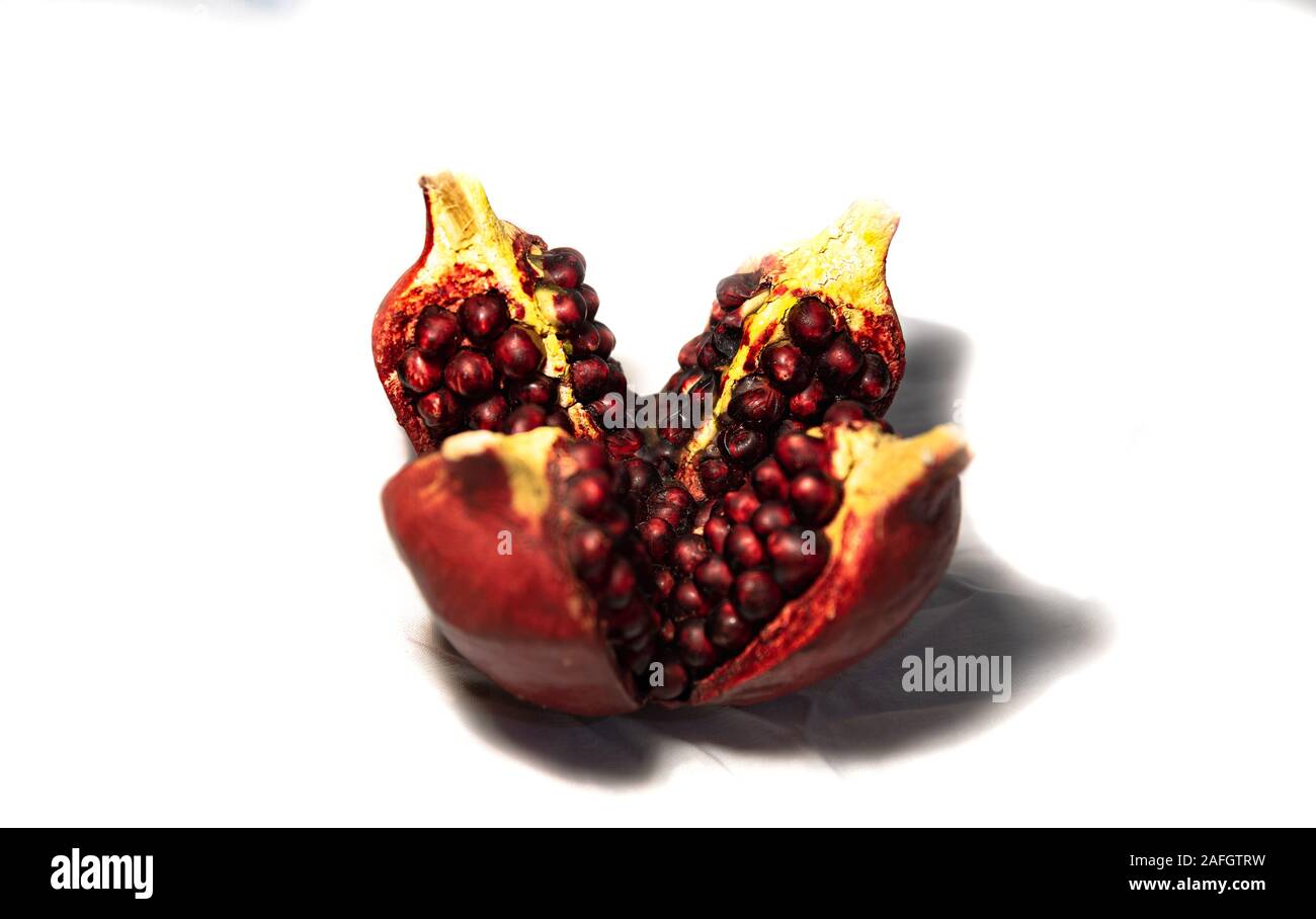 Maturity. Ripeness. The best age. Ripe red juicy pomegranate, divided into parts.  Concept. Stock Photo